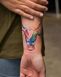 a woman's arm with a colorful cow tattoo on it