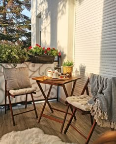 two chairs sitting on top of a wooden floor next to a table and potted plants