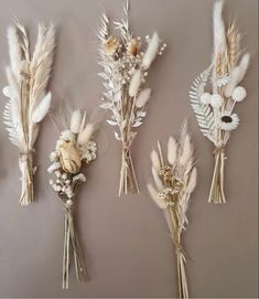 five dried flowers and feathers arranged in a row on a wall next to each other