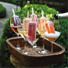 there are many different types of drinks in wine glasses on the trays and one is being filled with ice cream