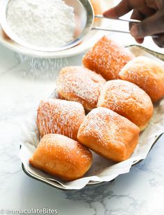 powdered sugar sprinkled on top of pastries in a metal bowl with spoon