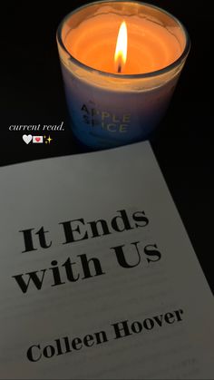 an open book next to a lit candle with the words it ends with us written on it