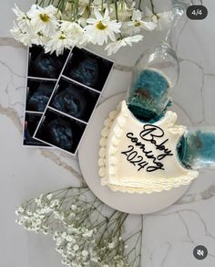 a birthday cake sitting on top of a white plate next to flowers and an album