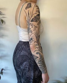 a woman with tattoos standing in front of a wall