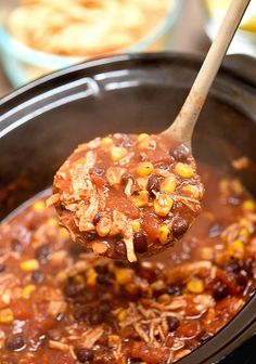 a spoon full of chili and corn in a slow cooker