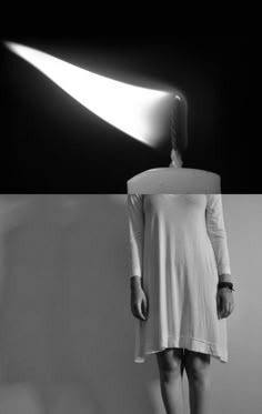 a black and white photo of a woman standing in front of a light that is shining on her head