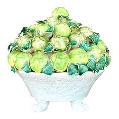 a white bowl filled with green apples on top of a table