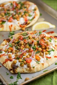 two pizzas with different toppings sitting on top of a tray next to each other