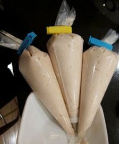 three pieces of food wrapped in plastic sitting on a white plate with blue and yellow handles