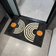 a black door mat with an orange and white design on the floor next to a doorway