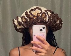 a woman taking a selfie in front of a mirror wearing a crocheted hat