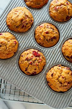 muffins with cranberries are sitting on a cooling rack, ready to be baked