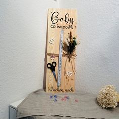 a wooden sign with scissors and flowers on it next to a flower pot filled with baby's breath