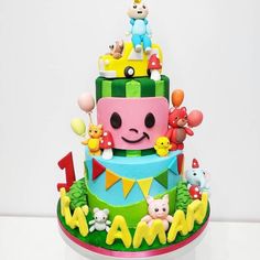 a multi layer cake decorated with toys and numbers on it's sides, sitting on a table