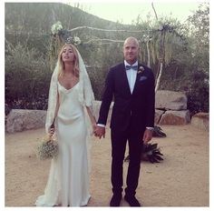 a bride and groom holding hands in the desert