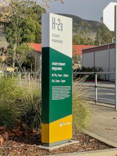 a green and yellow sign sitting on the side of a road next to a parking lot