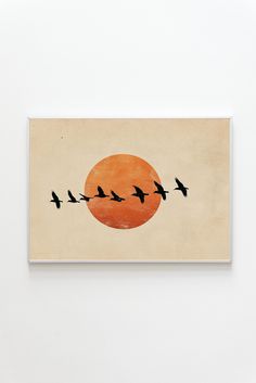 a painting with birds flying in front of an orange sun on a white wall above it