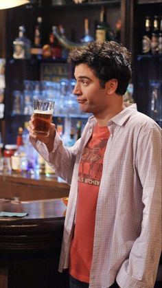 a man standing in front of a bar holding a glass with something in it's hand