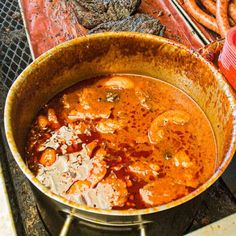 a large pot filled with food sitting on top of a stove next to hot dogs