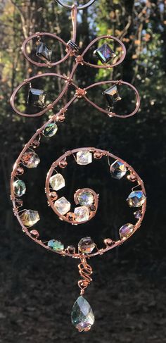 a wind chime hanging from the side of a tree with lots of crystals on it