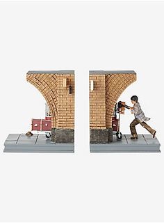 two miniature figurines of a man pushing a suitcase in front of a brick wall