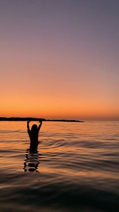 a person standing in the water with their arms above their head and hands behind their head