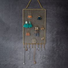 a metal rack with earrings hanging from it's sides on a gray wall next to a pair of scissors