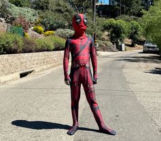 a man in a red and black costume is standing on the street