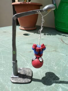 a toy hanging from a metal hook on a table next to a potted plant