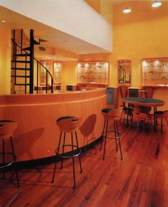 an empty restaurant with stools and tables in the center, along with stairs leading up to the second floor