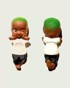 two small figurines with green hair and white shirt on top of each other