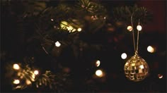 a disco ball ornament hanging from a christmas tree with lights in the background