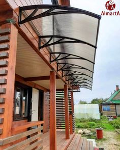 a wooden porch with metal railings on the top and bottom floor, along with an awning over the front door