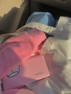 pink and blue items sitting on top of a white sheet in the back seat of a car