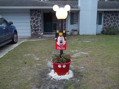 a mickey mouse planter in front of a house with a light on it's head