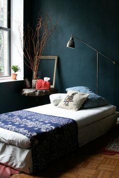 a bed sitting in a bedroom next to a window with a lamp on top of it