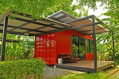 a red shipping container sitting on top of a lush green forest