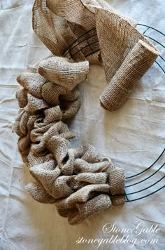 a wreath made out of burlocks on top of a white cloth covered table