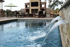 an outdoor swimming pool with a waterfall coming out of it