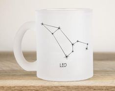 a coffee mug with the zodiac sign leo on it, sitting on a wooden table