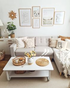 a living room with white furniture and pictures on the wall above it's coffee table