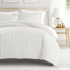 a bed with white and grey striped sheets