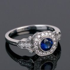 ✥ Art Deco Vintage Halo Engagement Ring, Bezel Set Milgrain Diamond Simulant Ring, Round Blue Sapphire Wedding Ring, Anniversary Gift For Her Metal : 925 Sterling Silver Plating : White Rhodium Plating Setting Type : Prong Setting ✥ Stone Details Stone Shape : Round Cut Gem Type :  Simulated Diamond (Cubic Zirconia) Carat Weight : 1.65 CTW Stone Color :  D/ White / Blue ( Eye Clean) Stone Clarity : VVS1 * Total Carat Weight : 1.65 CTW ✥ Policies & Note ✥ * Don't forget to read our store policies Antique Rings Art Deco, Platinum Sapphire Ring, Blue Sapphire Wedding Ring, Round Cut Diamond Ring, Edwardian Ring, Sapphire Wedding Rings, Engagement Rings Vintage Halo, Sapphire Rings, Art Deco Diamond Rings