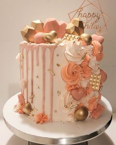 a white cake with pink and gold decorations on it's side, sitting on top of a table