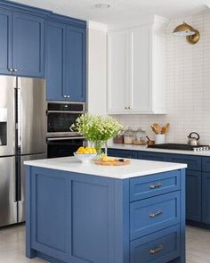 a kitchen with blue cabinets and an island in front of the stove, sink and refrigerator