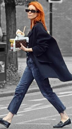 a woman with red hair is walking down the street while holding an ice cream sundae