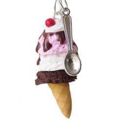 an ice cream sundae with chocolate sauce and cherry on top is hanging from a silver hook