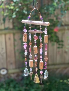 a wind chime hanging from a wooden pole with beads and charms attached to it