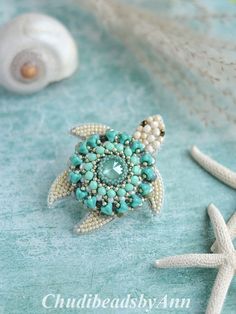 a sea turtle brooch sitting on top of a blue cloth next to starfish