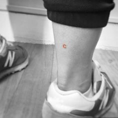 an orange dot is on the ankle of a person in black and white, standing next to a pair of running shoes